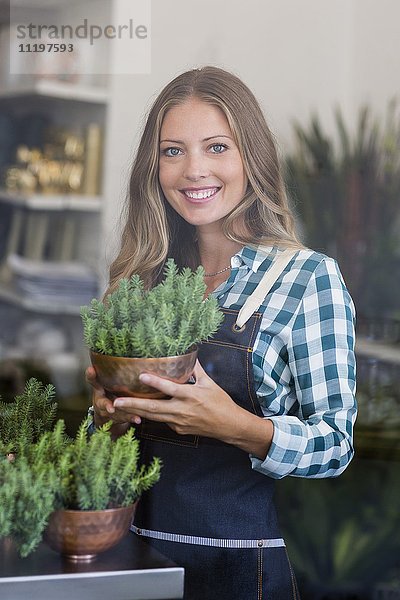 Porträt einer glücklichen Frau mit einer Topfpflanze