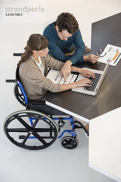 Zwei Geschäftsleute  die in einem Büro an einem Laptop arbeiten.