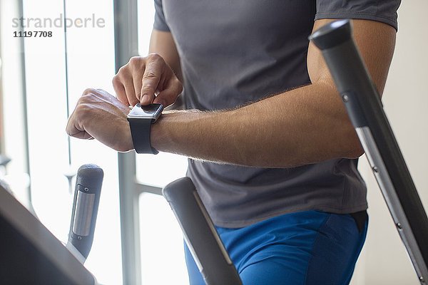 Mittelteilansicht eines Mannes mit intelligenter Uhr im Fitnessstudio