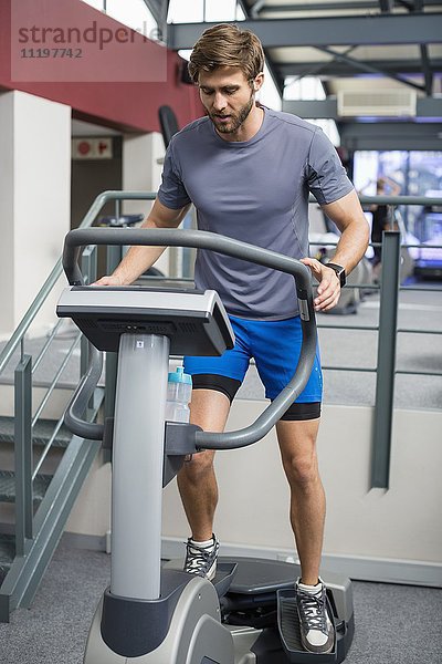 Mann trainiert die Beine mit einem Widerstand Gewicht Maschine in der Turnhalle