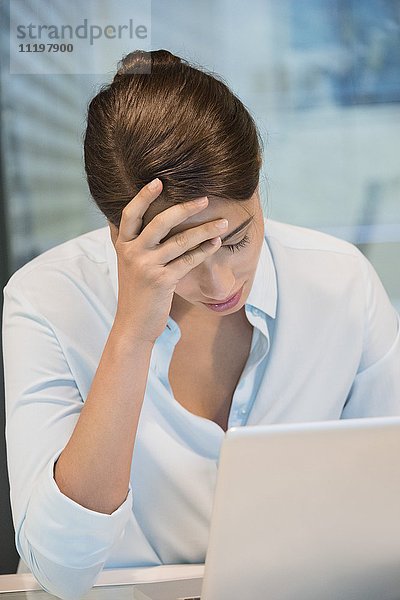 Stress Geschäftsfrau sitzt vor einem Laptop