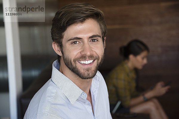 Porträt eines Geschäftsmannes lächelnd mit seinem Kollegen im Hintergrund
