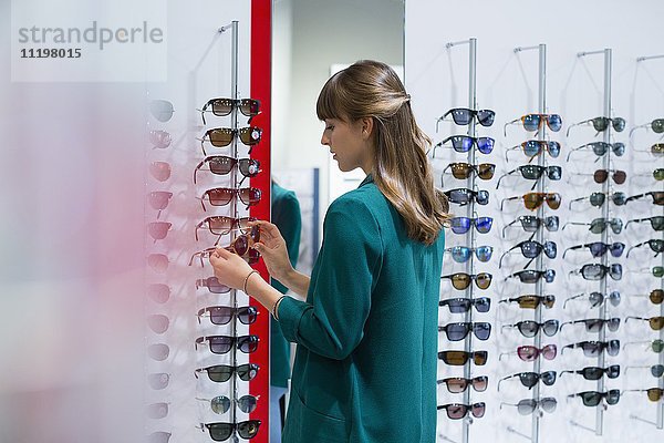 Junge Frau beim Sonnenbrillenkauf im Optikergeschäft