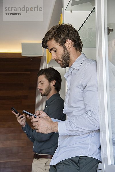 Zwei Geschäftsleute mit Mobiltelefonen im Büro