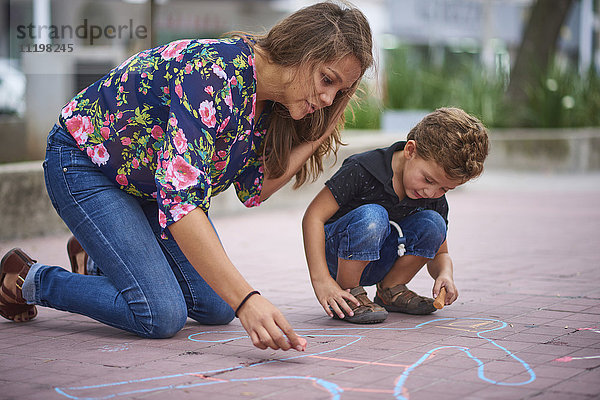 Hispanic Mutter und Sohn Zeichnung auf dem Bürgersteig mit Kreide