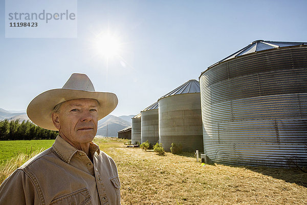 Seriöser kaukasischer Landwirt in der Nähe von Lagersilos