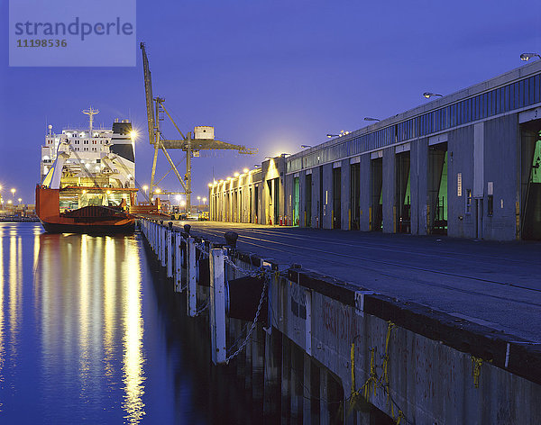 Frachtschiff unter Kran im Hafen bei Nacht