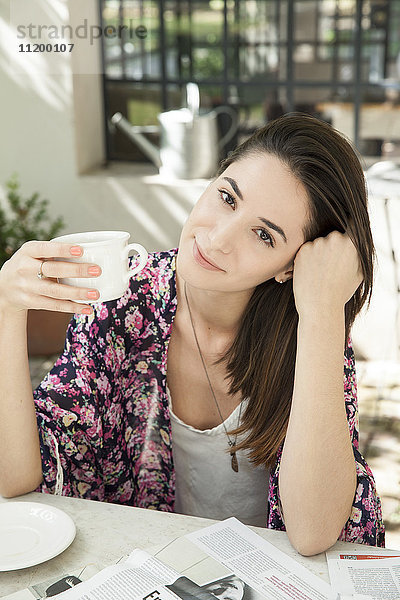 Junge Frau genießt eine Tasse Kaffee im Freien