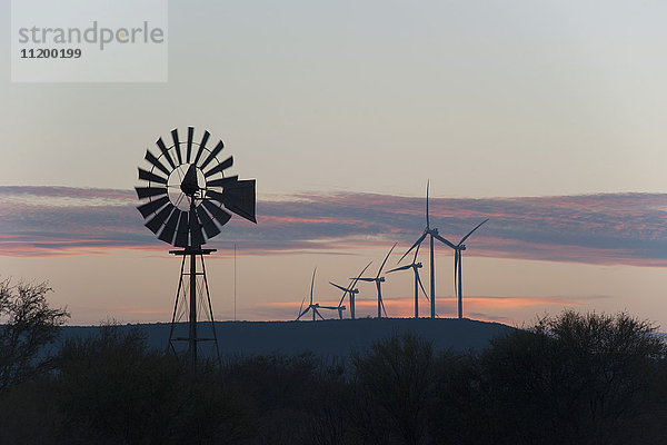 Ruhiger Blick auf eine altmodische Windmühle und moderne Windkraftanlagen gegen einen zwielichtigen Himmel