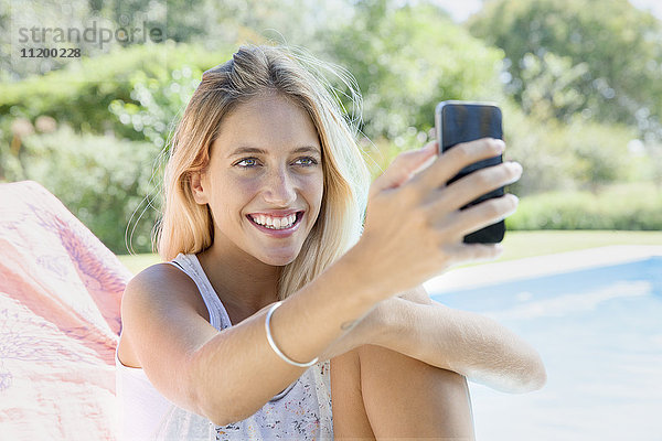 Frau mit Smartphone am Pool