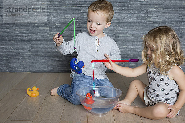 Kinder fangen mit Spielzeugangeln in einer großen Schüssel schwimmende Badeenten