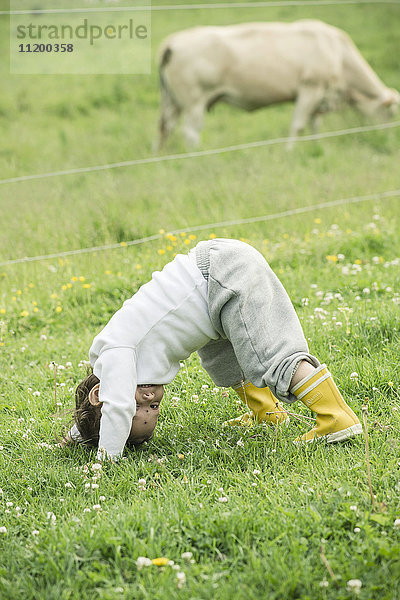 Kind spielt im Gras auf dem Bauernhof