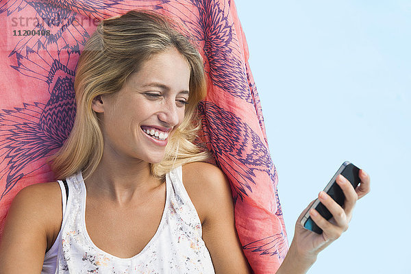 Frau Streaming-Video auf dem Smartphone beim Lounging am Pool