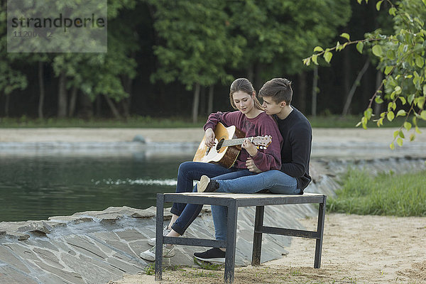 Liebender Mann  der sich mit seiner Freundin auf der Parkbank am See ausruht.