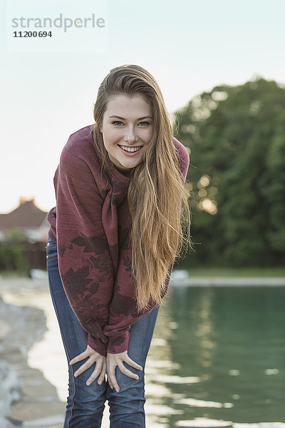 Porträt einer fröhlichen jungen Frau mit langen Haaren am See