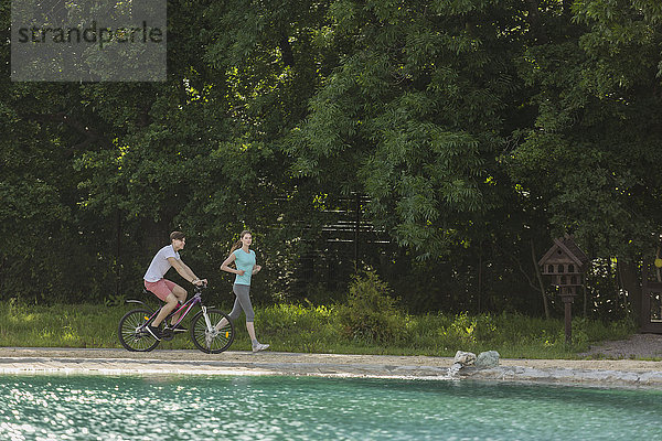 Frau beim Joggen beim Radfahren am See im Park