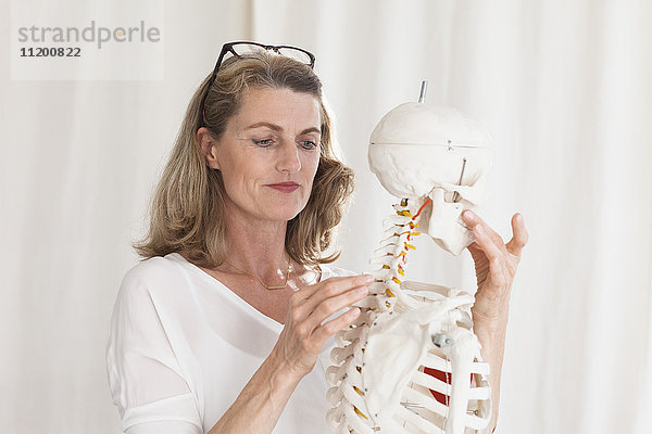 Selbstbewusste Ärztin beim Anblick des Skeletts im Stehen in der Klinik