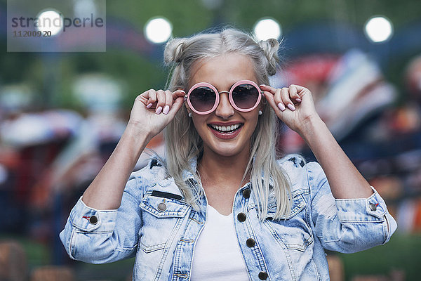 Portrait einer fröhlichen  modischen jungen Frau mit Sonnenbrille