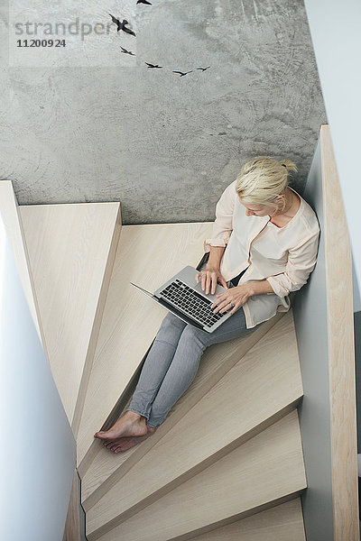 Frau mit Laptop auf einer Treppe sitzend