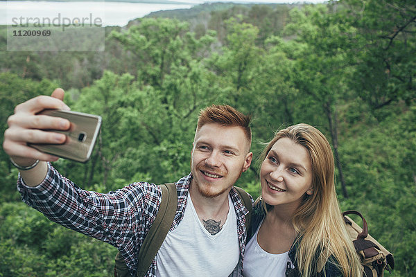 Lächelndes Paar nimmt Selfie durch Smartphone im Wald mit