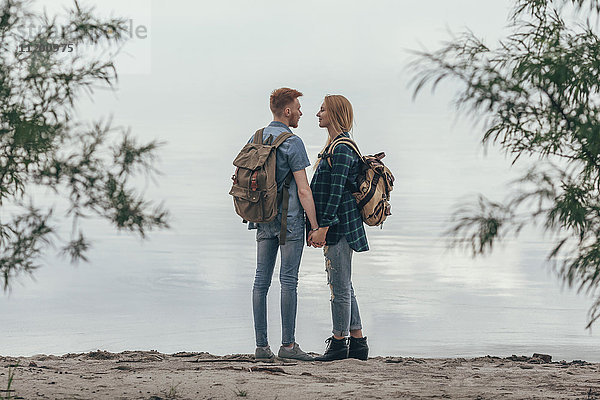 Paar hält sich an den Händen  während es am Seeufer steht