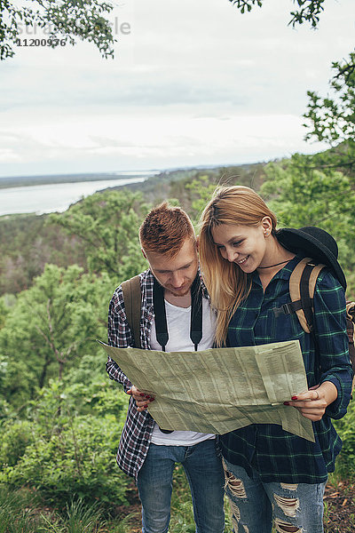 Lächelndes Paar liest Karte beim Wandern im Wald