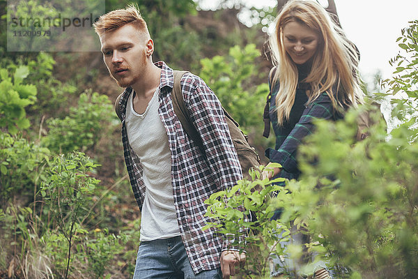Junges Paar beim Wandern inmitten von Pflanzen im Wald