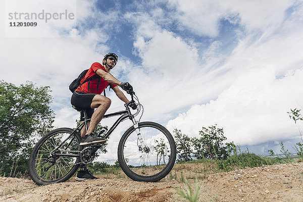 Tiefblick auf den Mann beim Mountainbikefahren in ländlicher Umgebung gegen den Himmel