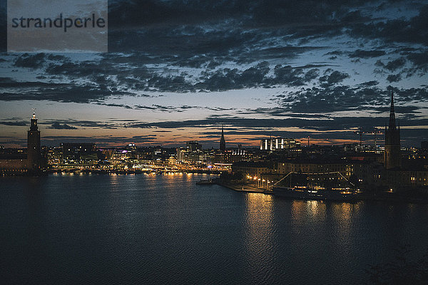 Szenische Ansicht der Uferpromenade und der beleuchteten Stadt gegen den Himmel in der Abenddämmerung  Stockholm  Schweden