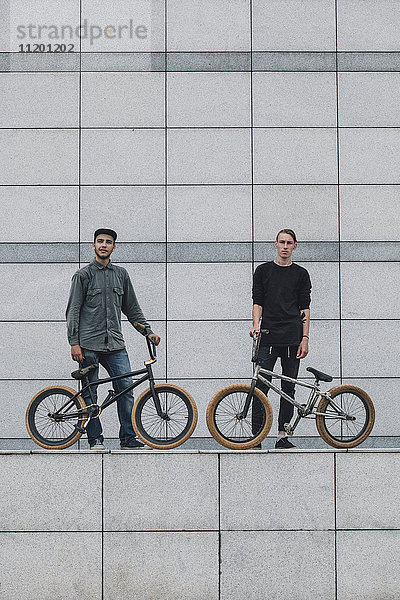 Selbstbewusste Teenager mit Fahrrädern an der Wand im Skateboard-Park