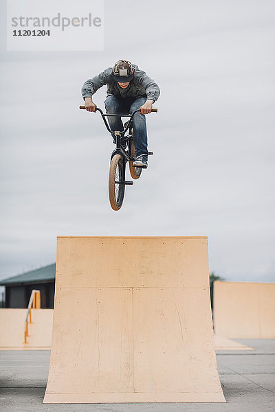 Teenager beim Stunt auf der Rampe im Skateboard-Park