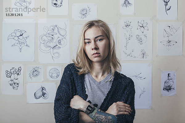 Porträt eines selbstbewussten Tätowierers  der sich gegen Entwürfe im Atelier stellt