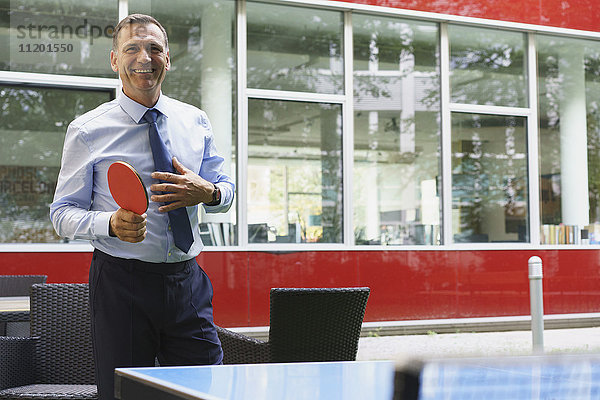 Lächelnder Geschäftsmann beim Tischtennisspielen im Kreativbüro