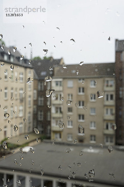 Gebäude gegen den Himmel durch nasses Glasfenster gesehen