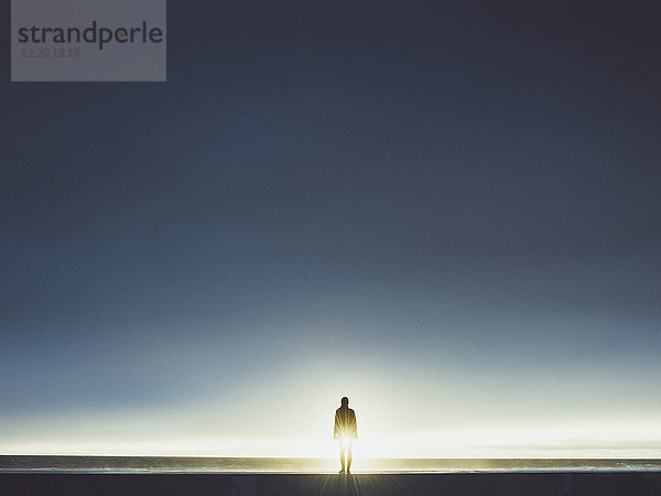 Silhouette Mann am Meer stehend gegen klaren Himmel bei Sonnenschein