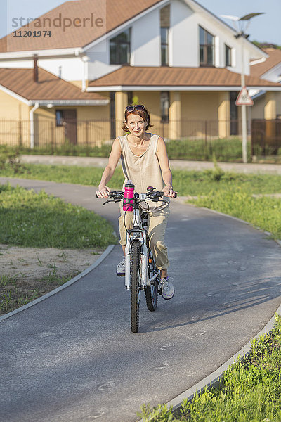 Porträt einer Radfahrerin auf der Straße gegen das Haus