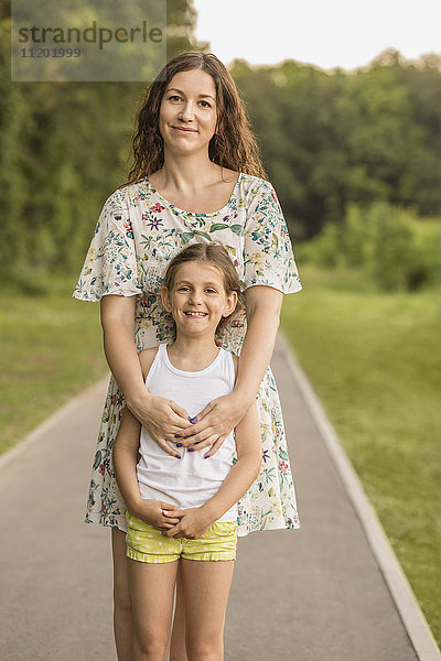 Porträt einer schönen Frau und Tochter auf einem Wanderweg im Park