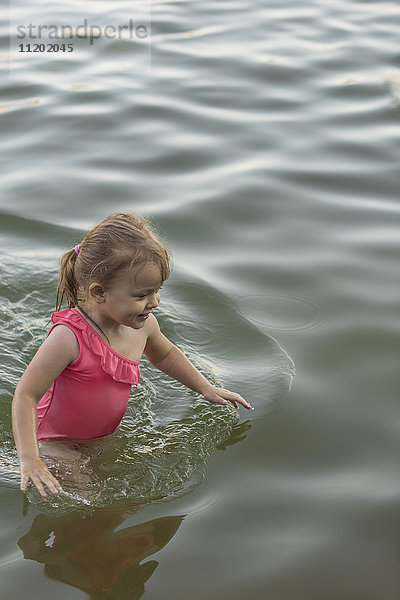 Fröhliches Mädchen in rosa Badeanzug stehend im See