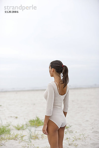 Junge Frau im Bodysuit und am Strand stehend