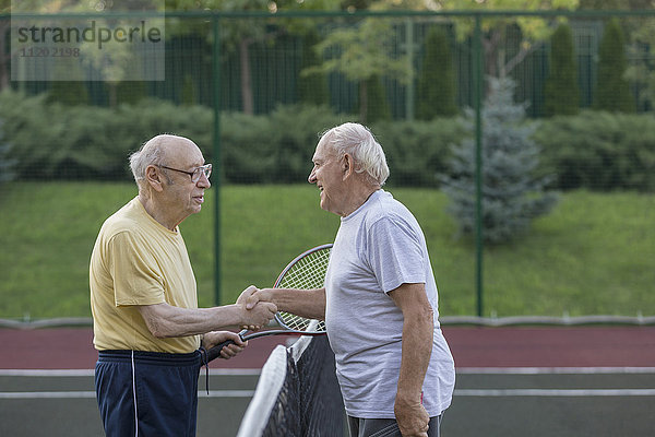 Seniorenfreunde beim Händeschütteln am Tennisplatz