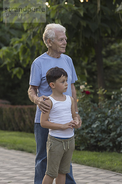 Lächelnder Großvater stehend mit Enkel auf dem Fußweg im Park