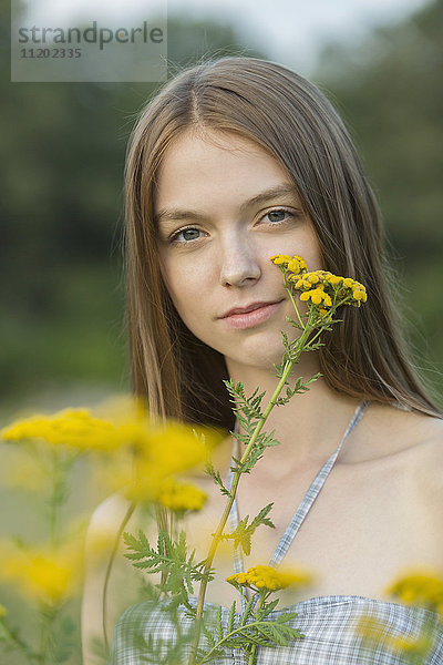Porträt einer schönen Frau mit gelben Blumen im Park