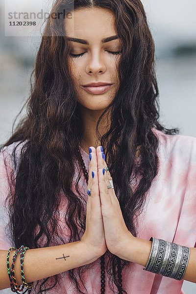 Junge Frau mit geschlossenen Augen praktiziert Yoga in Gebetshaltung