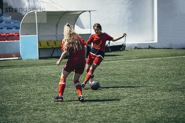 Entschlossene Teenager spielen Fußball auf dem Spielfeld