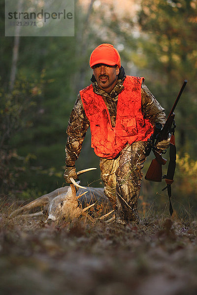 Whitetail Deer Hunter schleppt Hirsch aus dem Feld