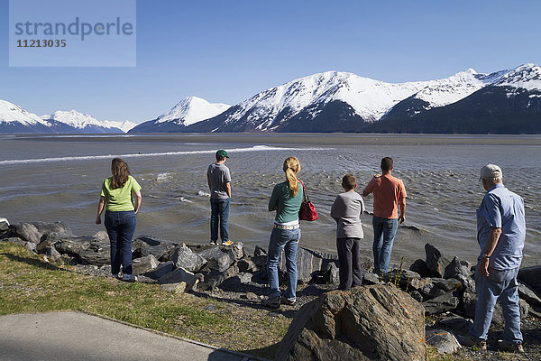 Eine Gruppe von Menschen beobachtet  wie eine kleine Flutwelle an ihnen vorbeizieht  während sie von einem Rastplatz am Seward Hwy aus zusehen  Süd-Zentral-Alaska  USA