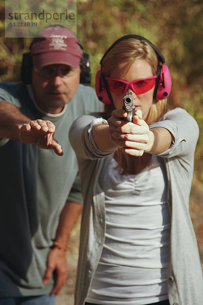 Frau wird auf dem Schießstand mit einer Handfeuerwaffe unterrichtet