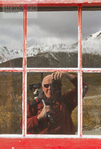 Reflexion des Fotografen im Fenster des Gebäudes der Independence Mine in Hatcher Pass  Southcentral Alaska  USA