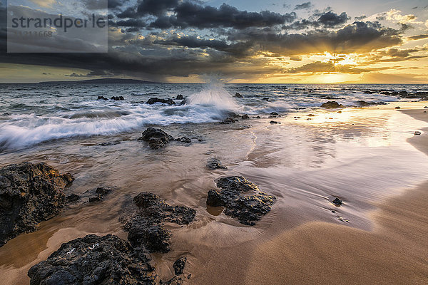 Wasser plätschert am Strand mit einem goldenen Sonnenuntergang über dem Ozean; Hawaii  Vereinigte Staaten von Amerika'.