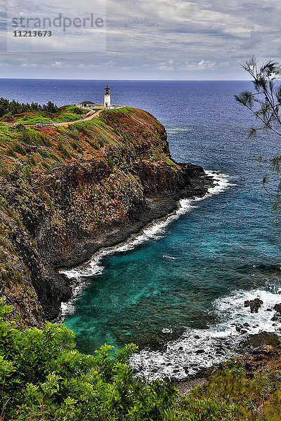 Ein Leuchtturm am Ende eines Weges oberhalb einer Klippe entlang der Küste  Kilauea Point; Hawaii  Vereinigte Staaten von Amerika'.